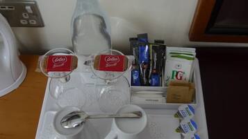 Una bandeja con una botella de agua, dos tazas de café, sobres de azúcar y una cuchara.