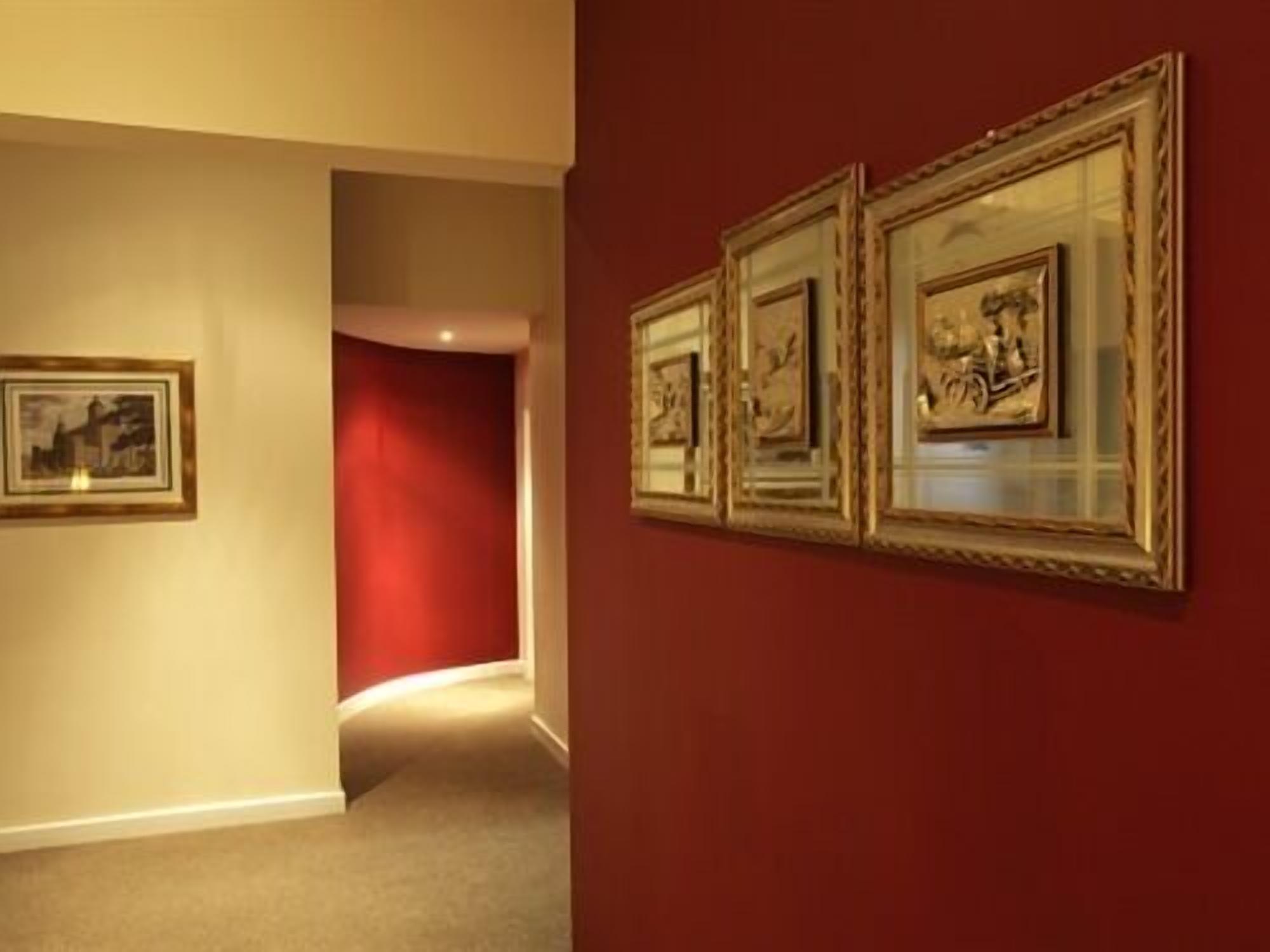 A hallway with framed artwork on the walls and a red accent wall.