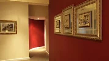 A hallway with framed artwork on the walls and a red accent wall.
