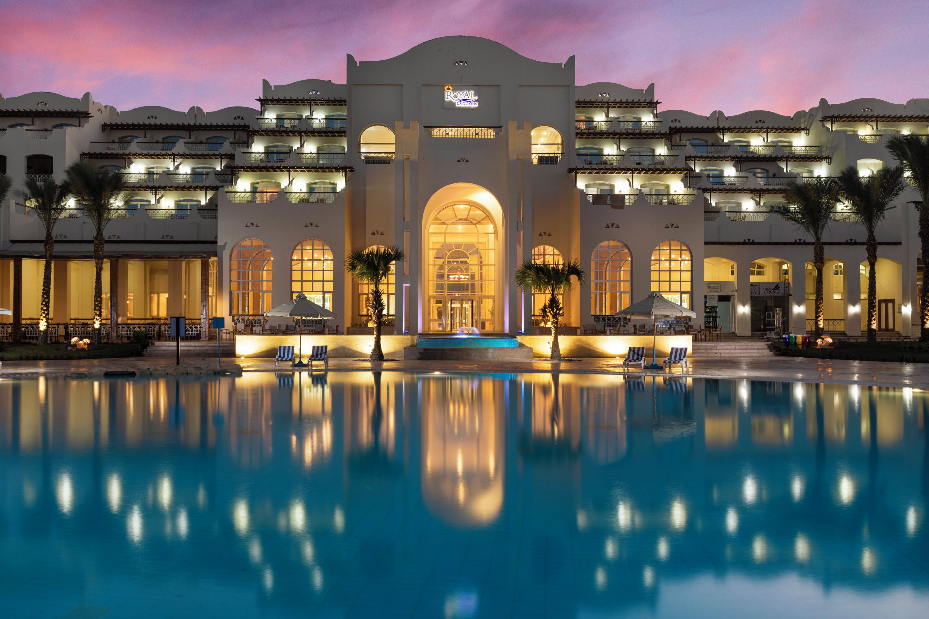 A hotel with a large pool, multiple balconies, and a grand entrance.