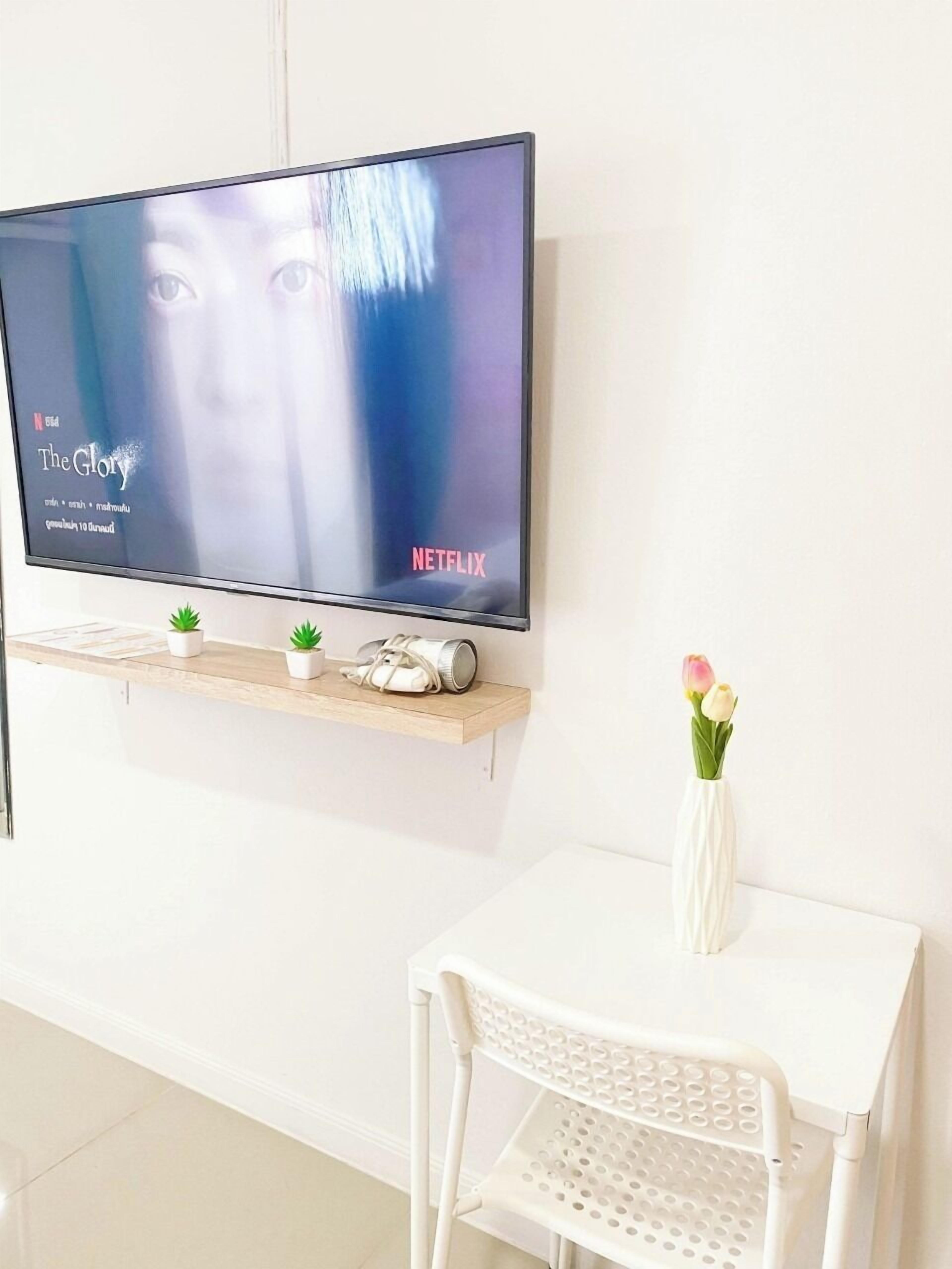 A flat-screen TV mounted on a wall, displaying 'The Glory' on Netflix.
