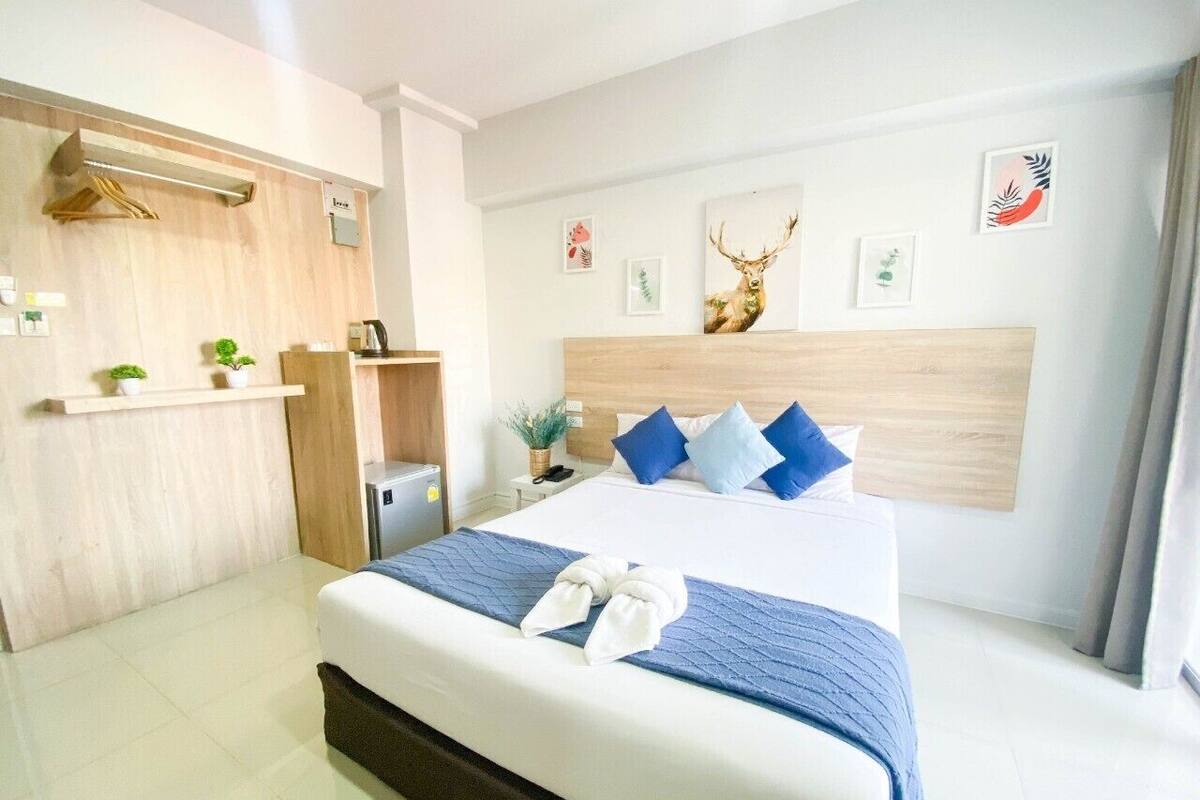 A hotel room with a bed, a desk, and a headboard with artwork.