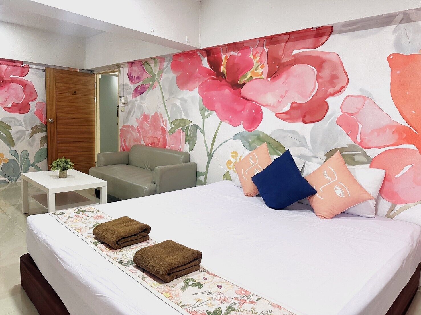 Ein Schlafzimmer mit einem Bett, einer Couch, einem kleinen Tisch und einer Tür.