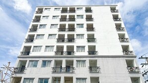 Edificio de 48 Ville con diseño moderno, que presenta fachada plana, varios balcones y una entrada a nivel de calle con asientos al aire libre.