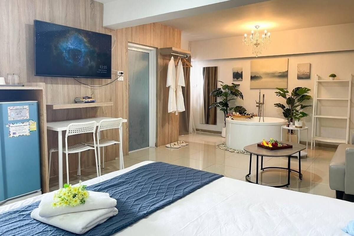 A modern hotel room with a bed, a desk, a TV, a shower, and a bathtub.