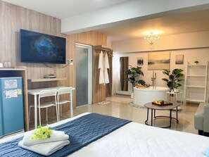 Une chambre d’hôtel moderne équipée d’un lit, d’un bureau, d’une télévision, d’une douche et d’une baignoire.