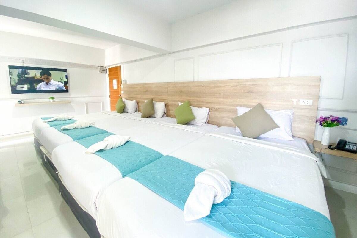 A hotel room with a large bed, a television, and a wooden headboard.