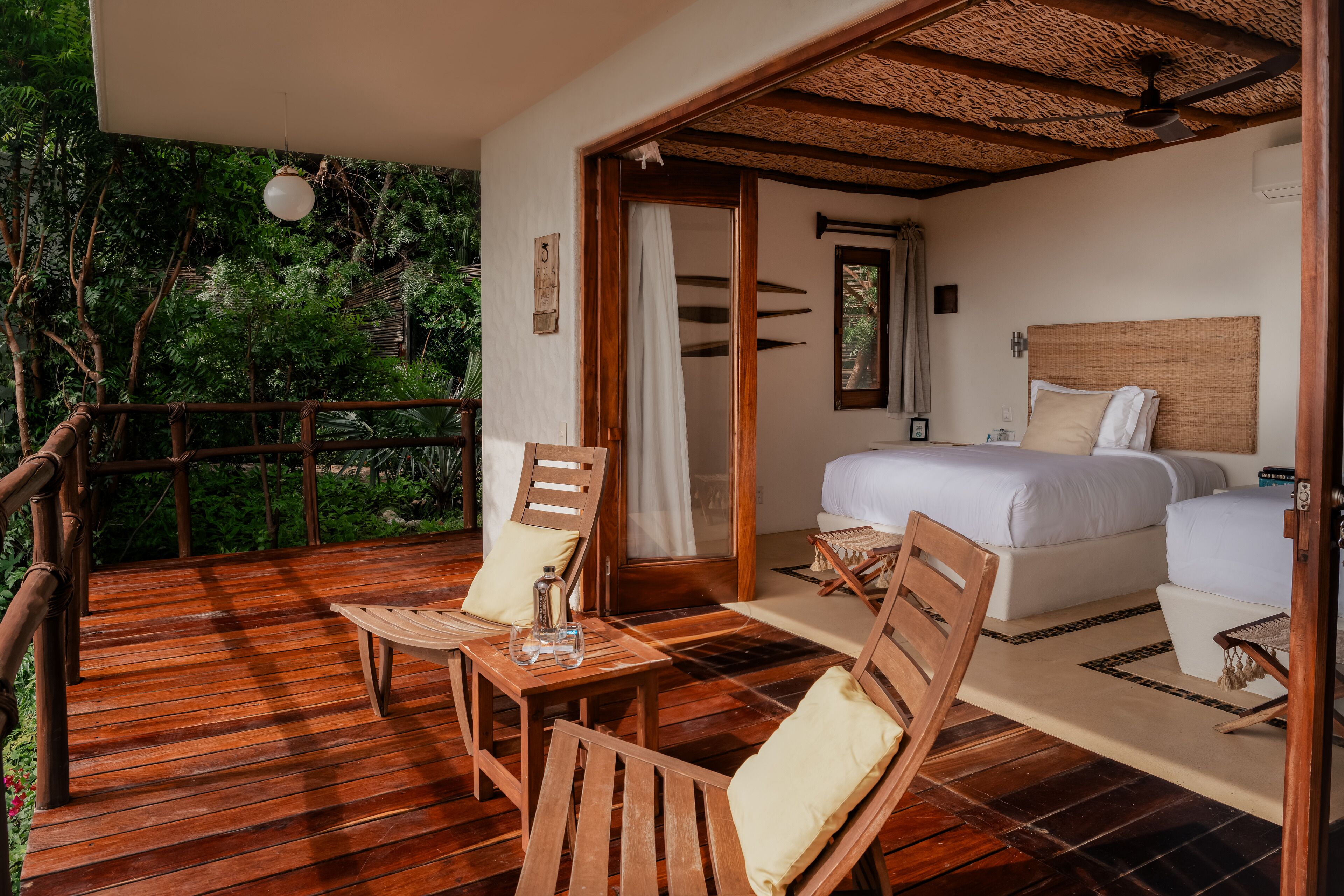 A wooden deck with a bed, two chairs, and a table.