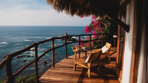 Una terraza de madera con mesa y sillas con vista al océano.