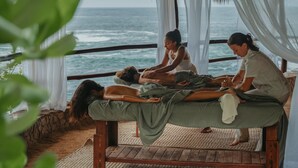 A massage therapy session on a wooden platform with a view of the ocean.