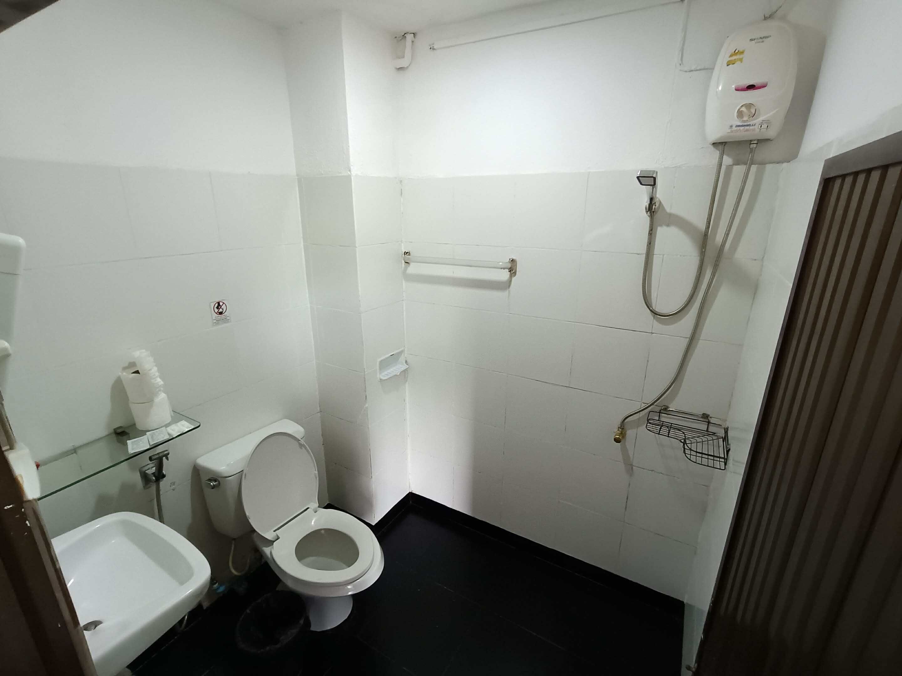 A small, clean bathroom with a toilet, bidet, and a glass shelf with toiletries.