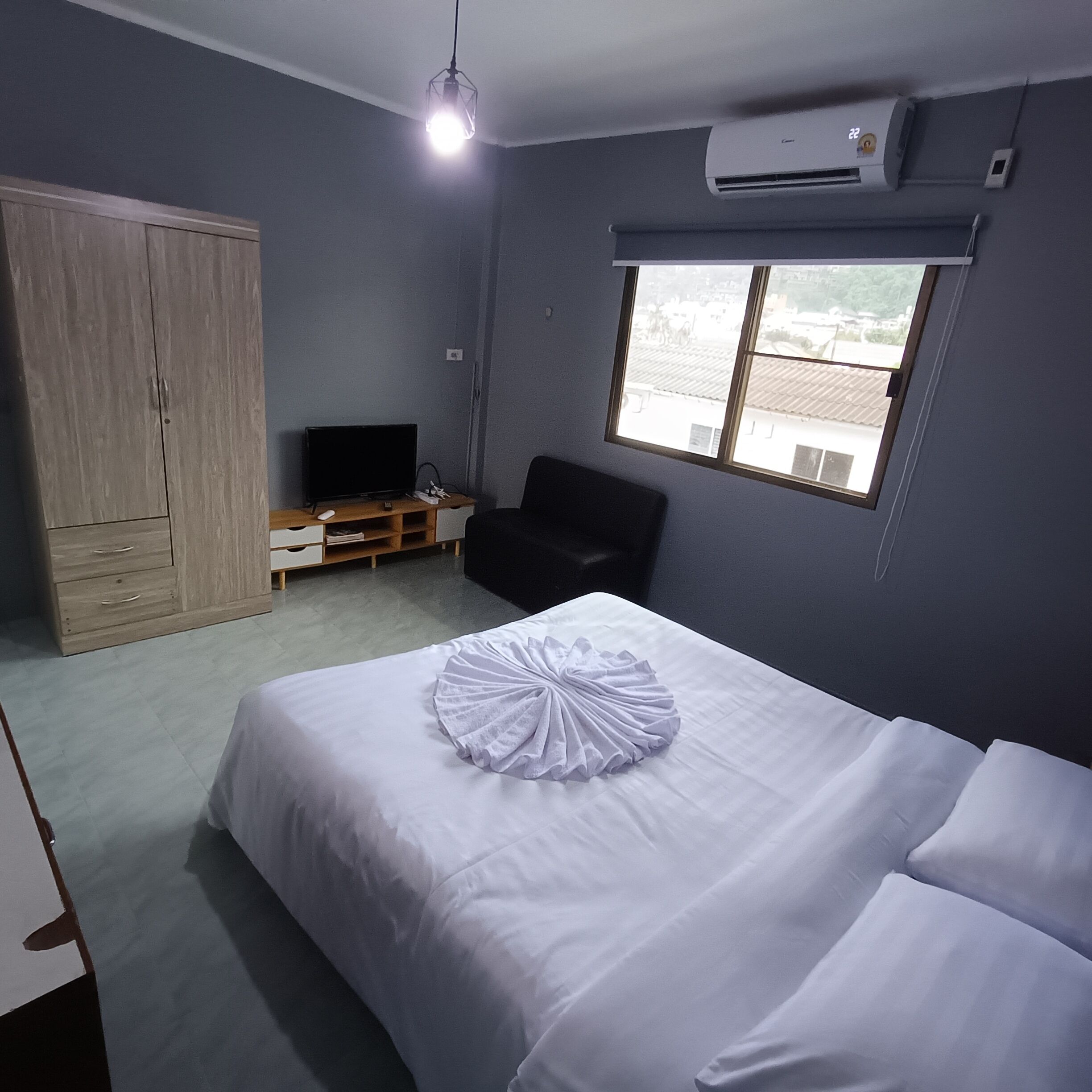 Een slaapkamer met een bed, een televisie, een kledingkast, een stoel en een raam.