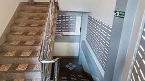 A staircase with a metal railing, fire exit signs, and a fire extinguisher. - The Guest House  (Patong)