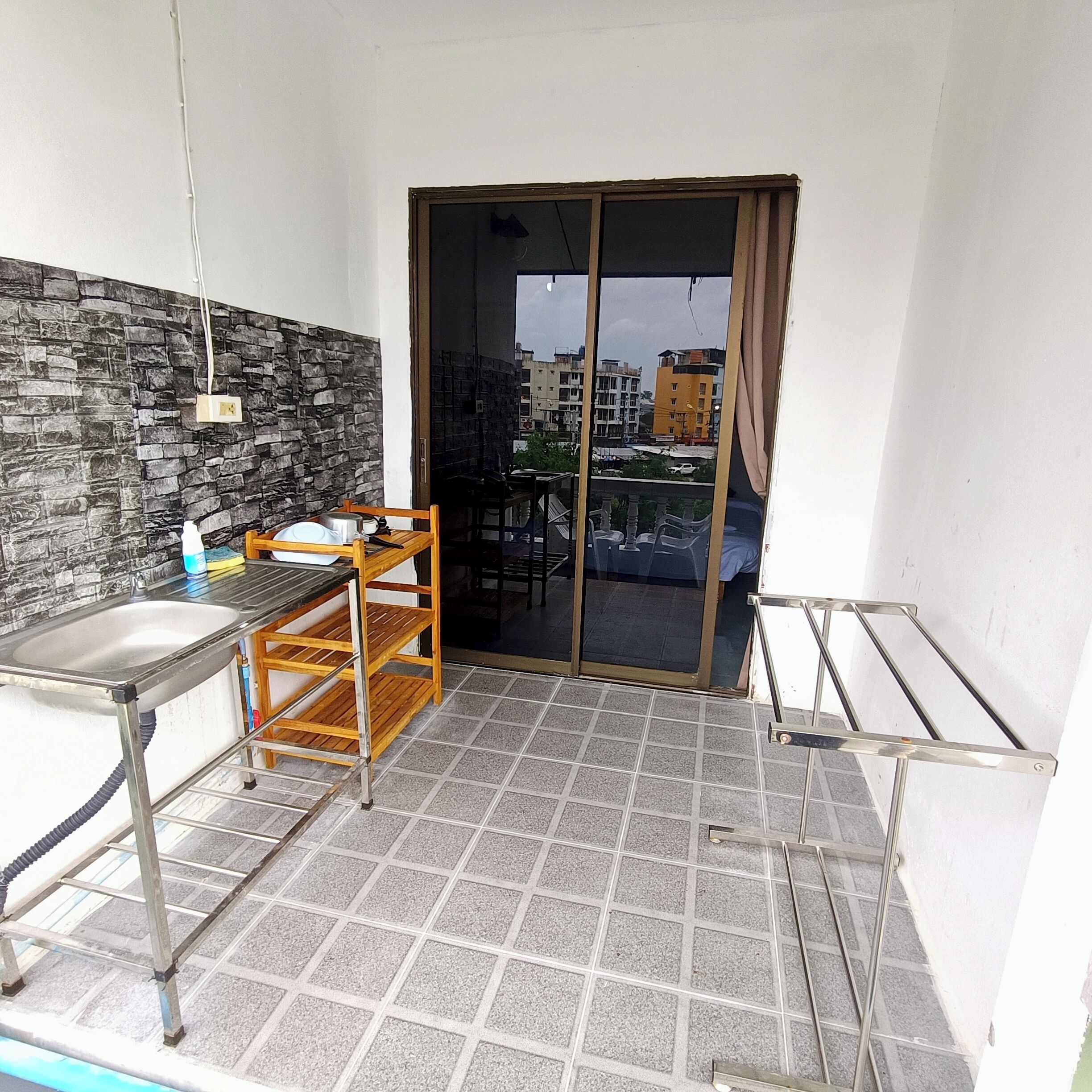 A balcony with a sink, a wooden chair, and a table.