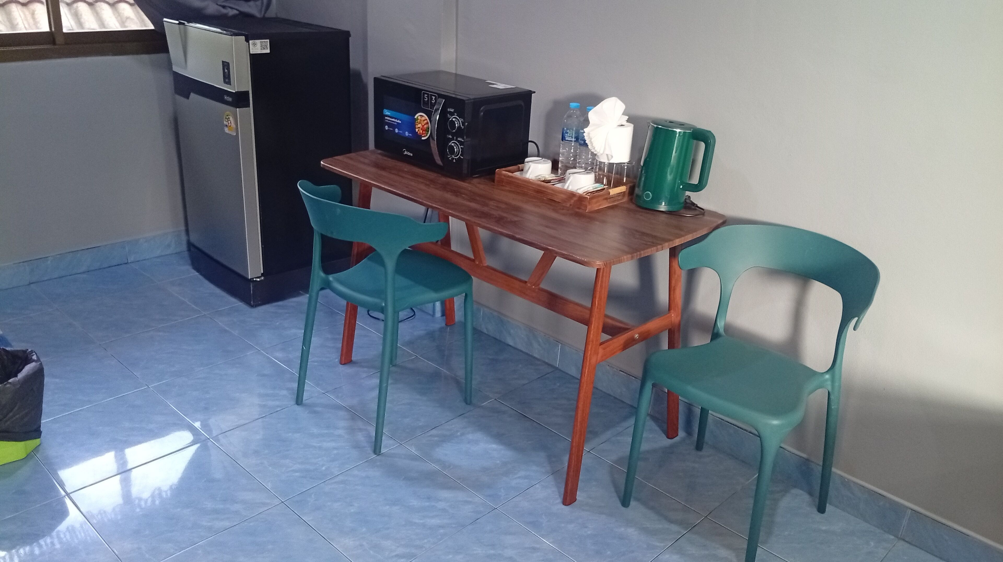 A small kitchenette with a refrigerator, microwave, and coffee maker. There are two chairs and a table.