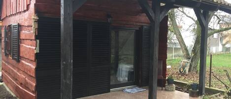 A wooden house with a covered porch, black shutters, and a tiled entrance.