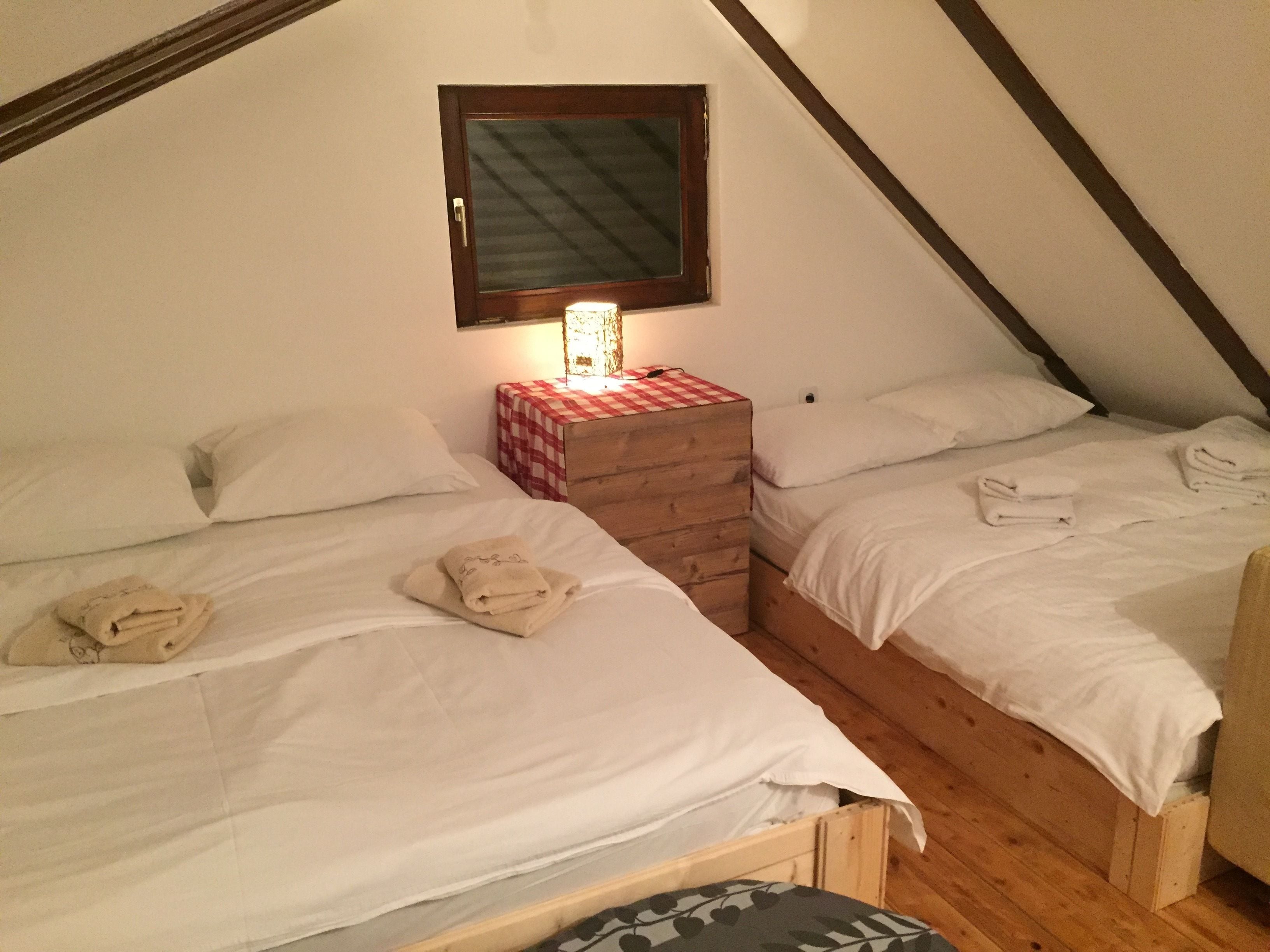 Ein kleiner, gemütlicher Raum mit zwei Einzelbetten, einem Holzschrank und einem Fenster mit Spiegel.