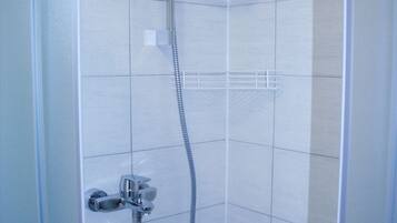 A shower with a handheld showerhead and a fixed showerhead, both mounted on a wall.