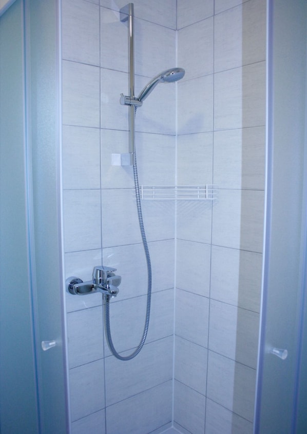 A shower with a handheld showerhead and a fixed showerhead, both mounted on a wall.