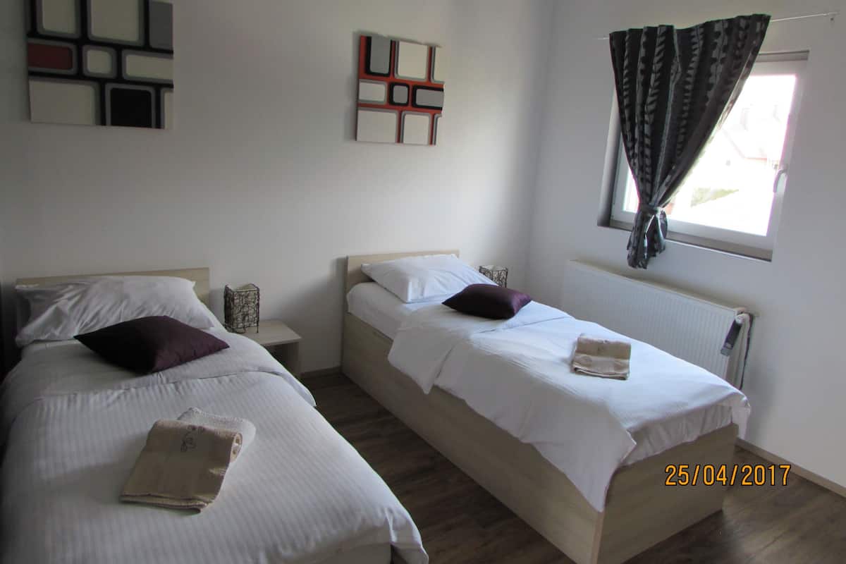 Une chambre avec deux lits, un radiateur et une fenêtre avec des rideaux.