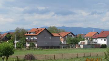 Zona residencial amb cases, un camp de gespa i muntanyes al fons.