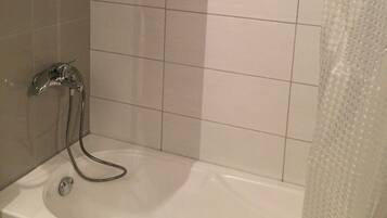 A bathroom with a bathtub, a shower curtain, and tiled walls.