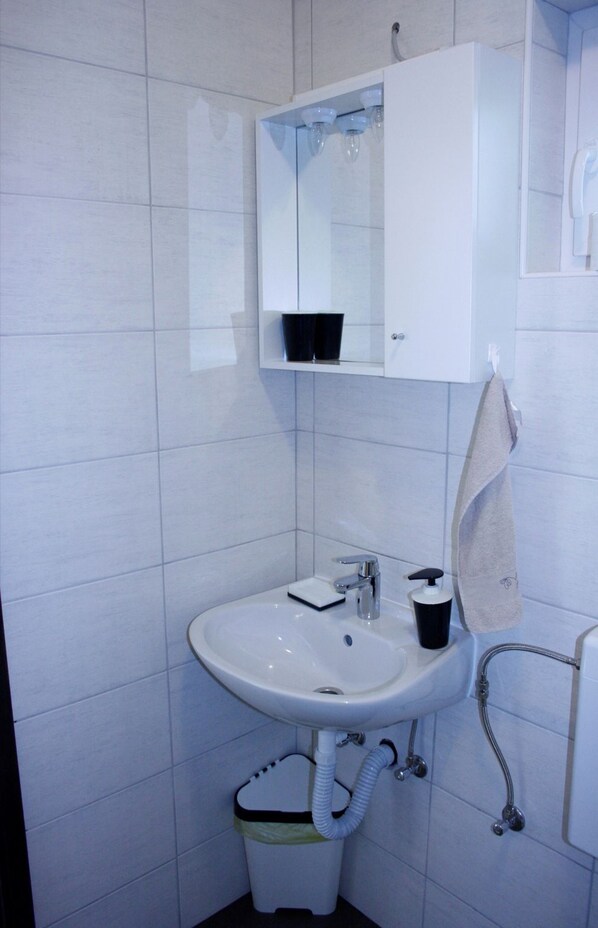 A bathroom with a white sink, a mirror above it, and a towel hanging on a rack.