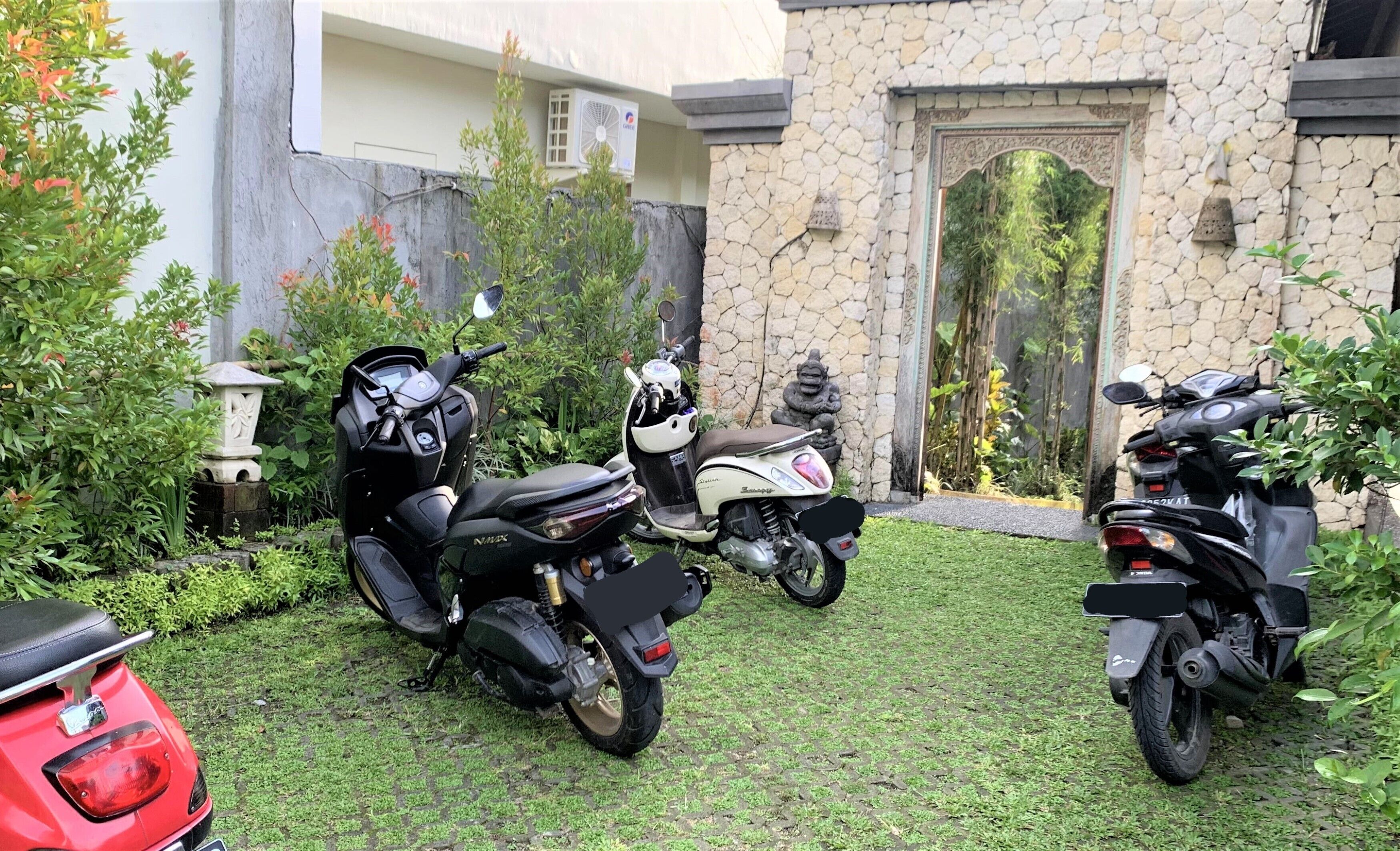 A garden with two motorcycles parked near a stone building with a decorative door.