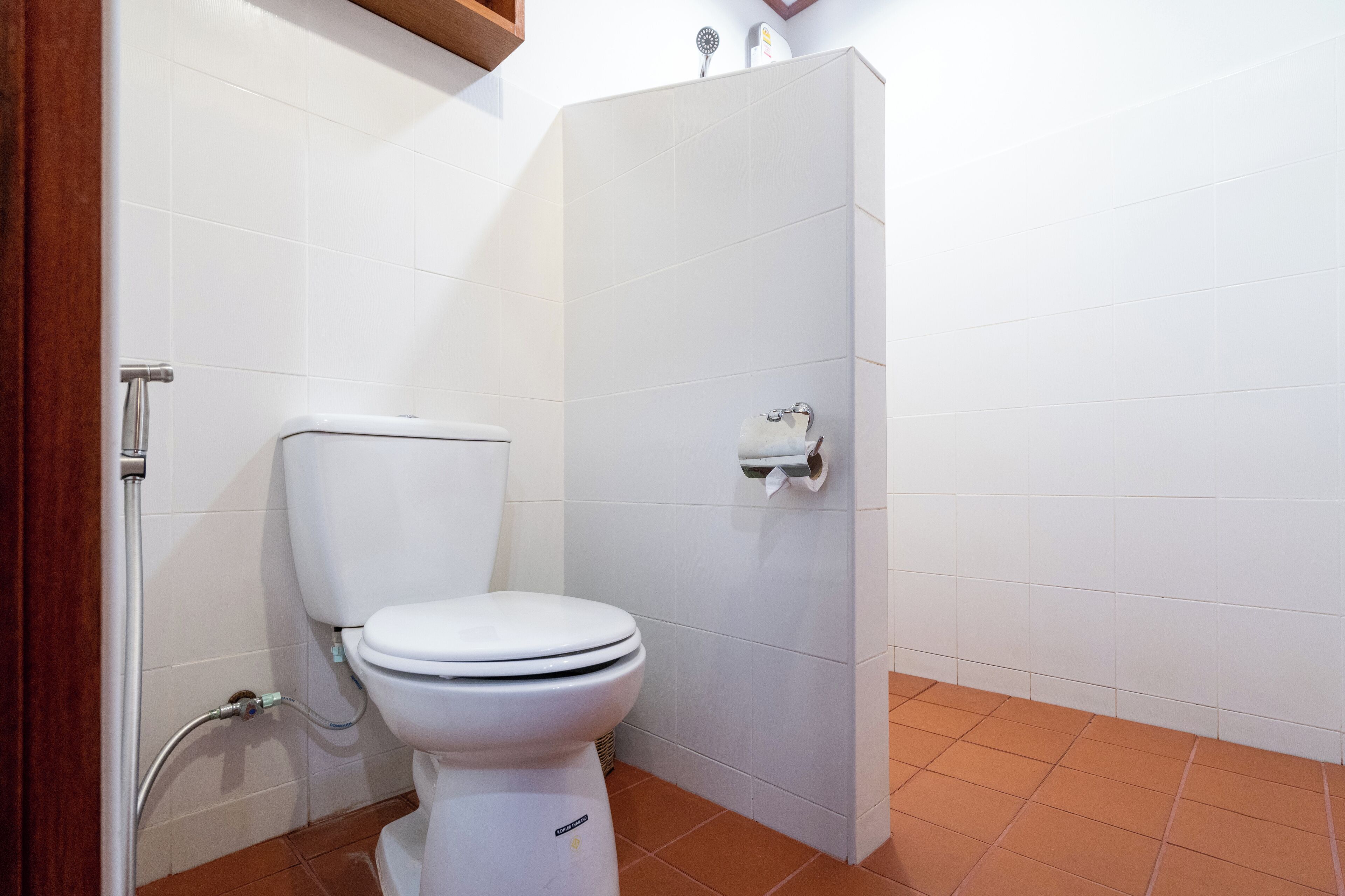 Egy fürdőszoba, amelyben fehér WC-papír található, egy zuhanyzó, és a falon egy tekercs WC-papír van.