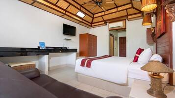 Una habitación de hotel con cama, escritorio, televisor y ventilador de techo.