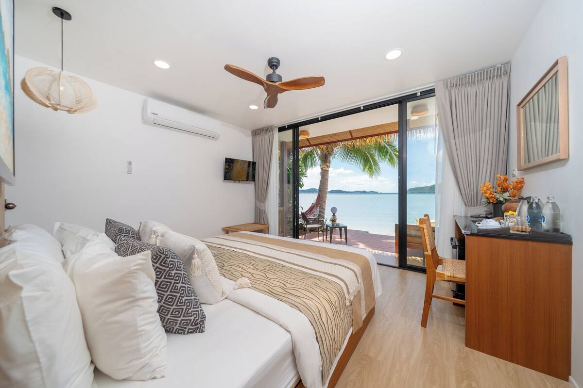 Une chambre avec un lit, un bureau et une vue sur la mer.