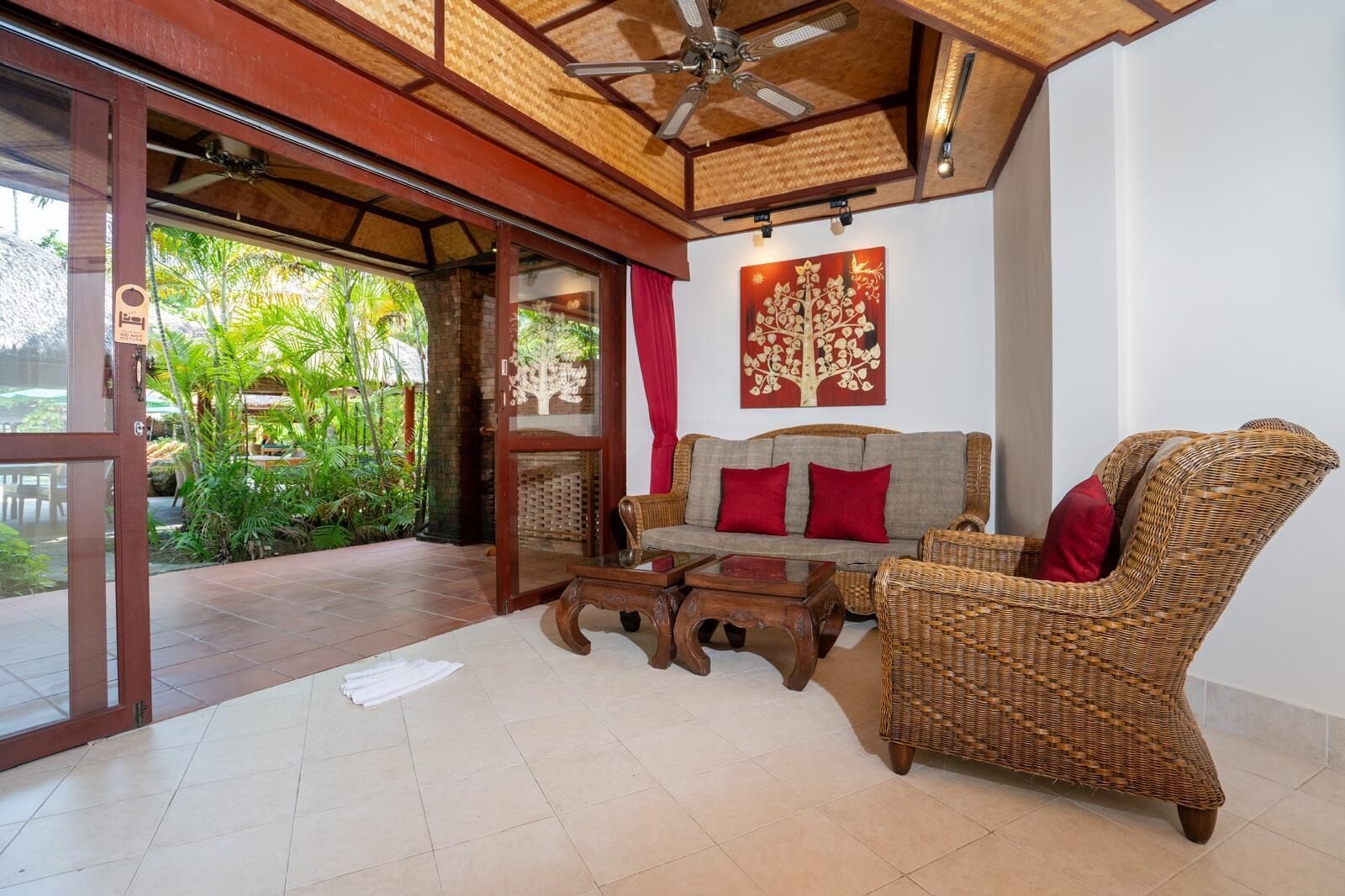 Un vaste espace de vie comprenant un canapé, des fauteuils et une table basse. Une porte vitrée donne accès à un jardin extérieur.