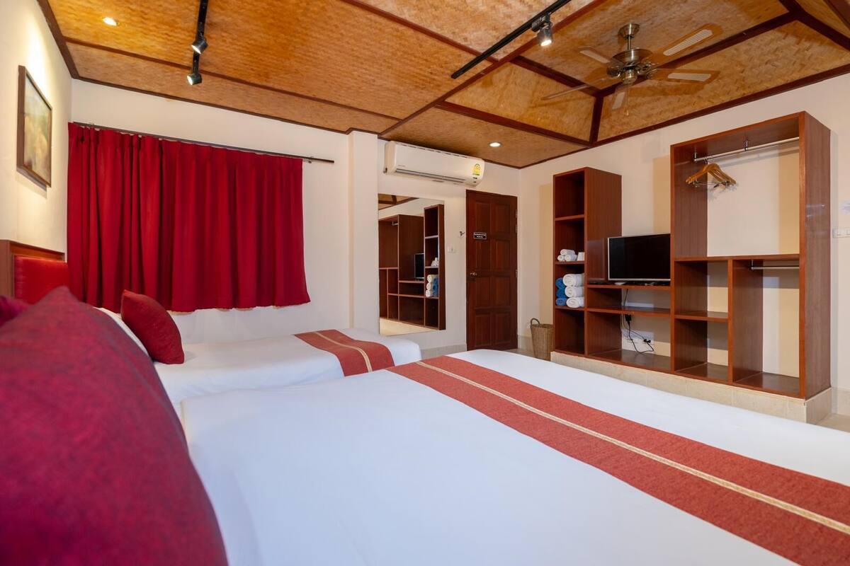 Une chambre d’hôtel avec deux lits, une armoire, un téléviseur et un appareil de climatisation.