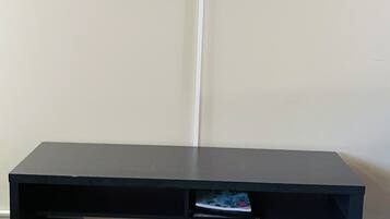 A flat-screen TV mounted on a white wall with a black entertainment unit below it.