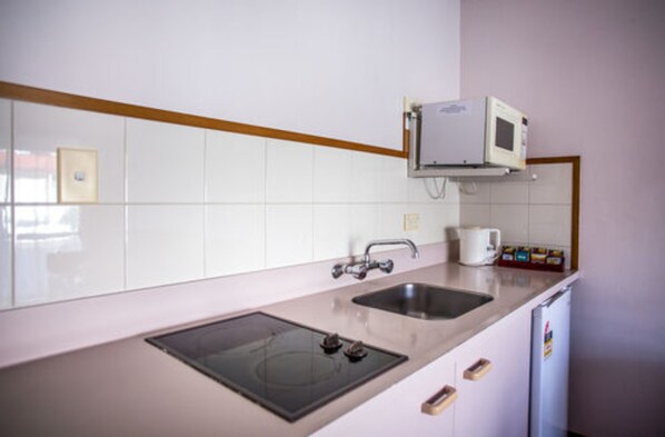 A kitchen with a microwave, sink, and stove.