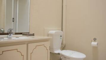 A bathroom with a toilet, sink, and cabinet.
