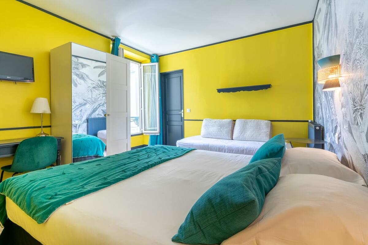 Habitación de hotel con dos camas, un escritorio, una silla, un televisor y un armario.