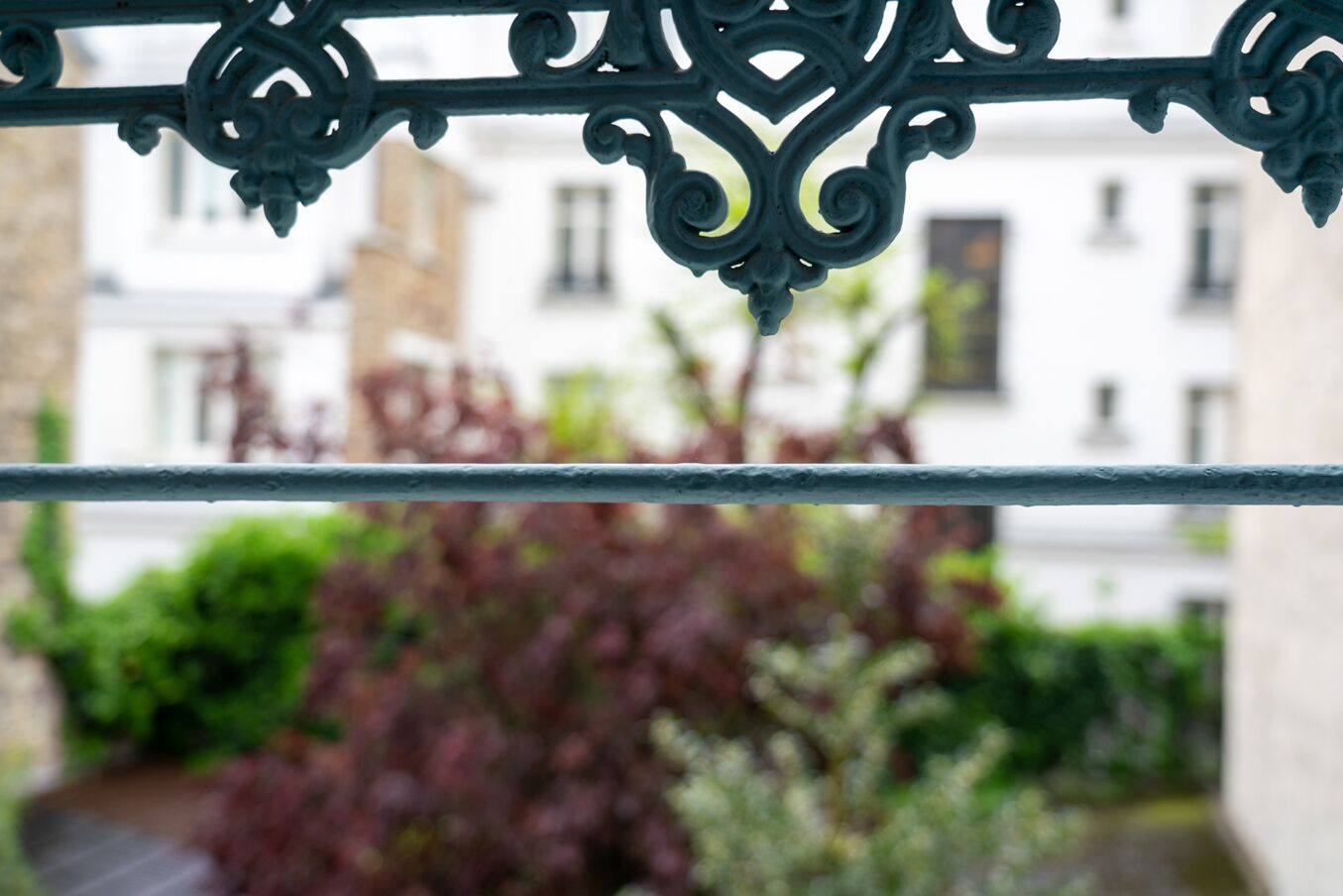 A balcony railing with a view of a building and greenery.