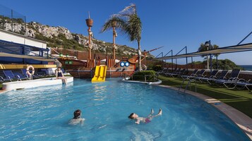 Una piscina al aire libre, sillones reclinables de piscina