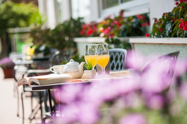 A table with a book, a teapot, a cup, and two glasses of orange juice. - Hotel Virginia (Diano Marina)