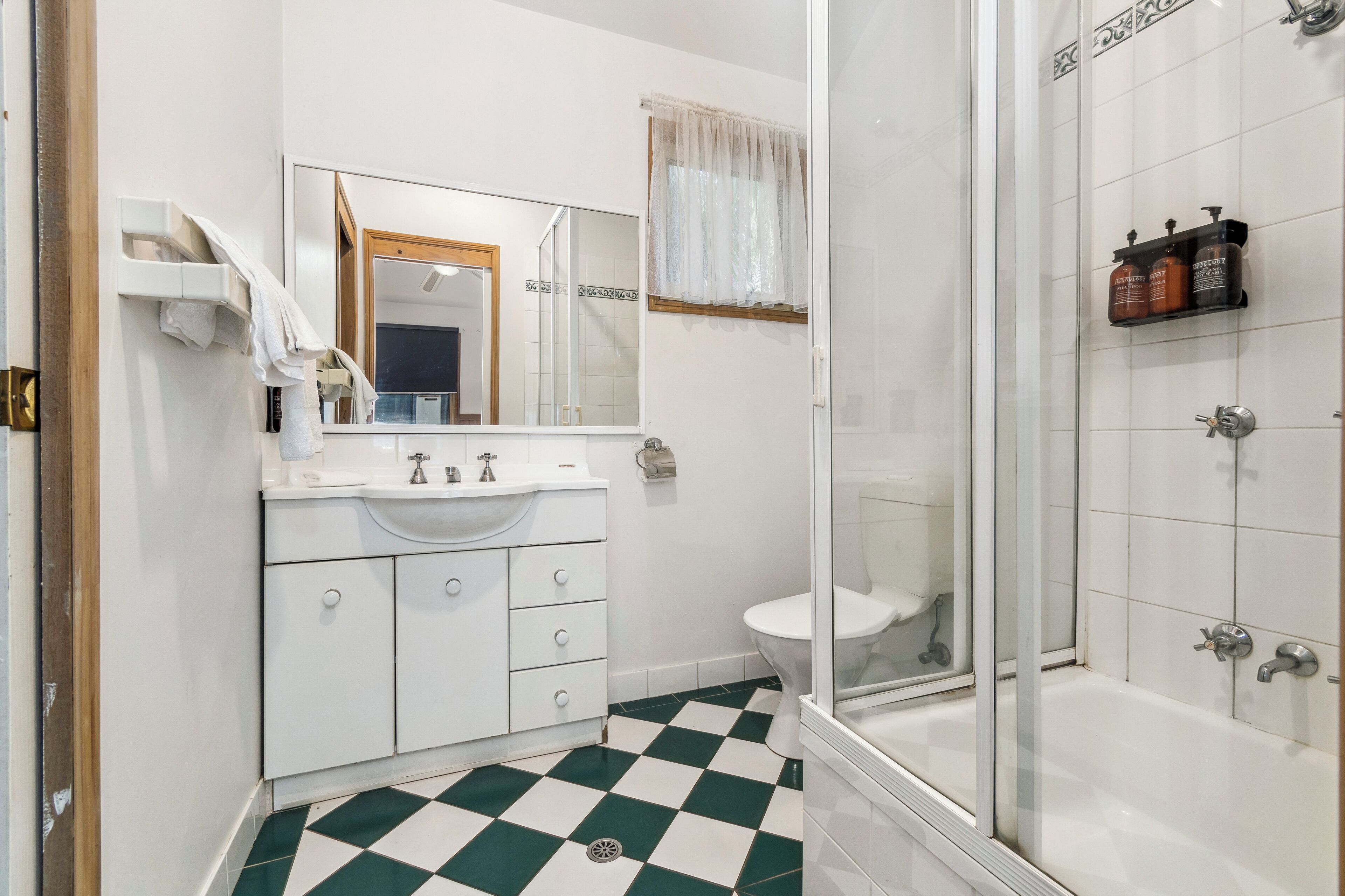 A bathroom with a white sink, mirror, and toilet. There is a shower area with a glass door and a bathtub.