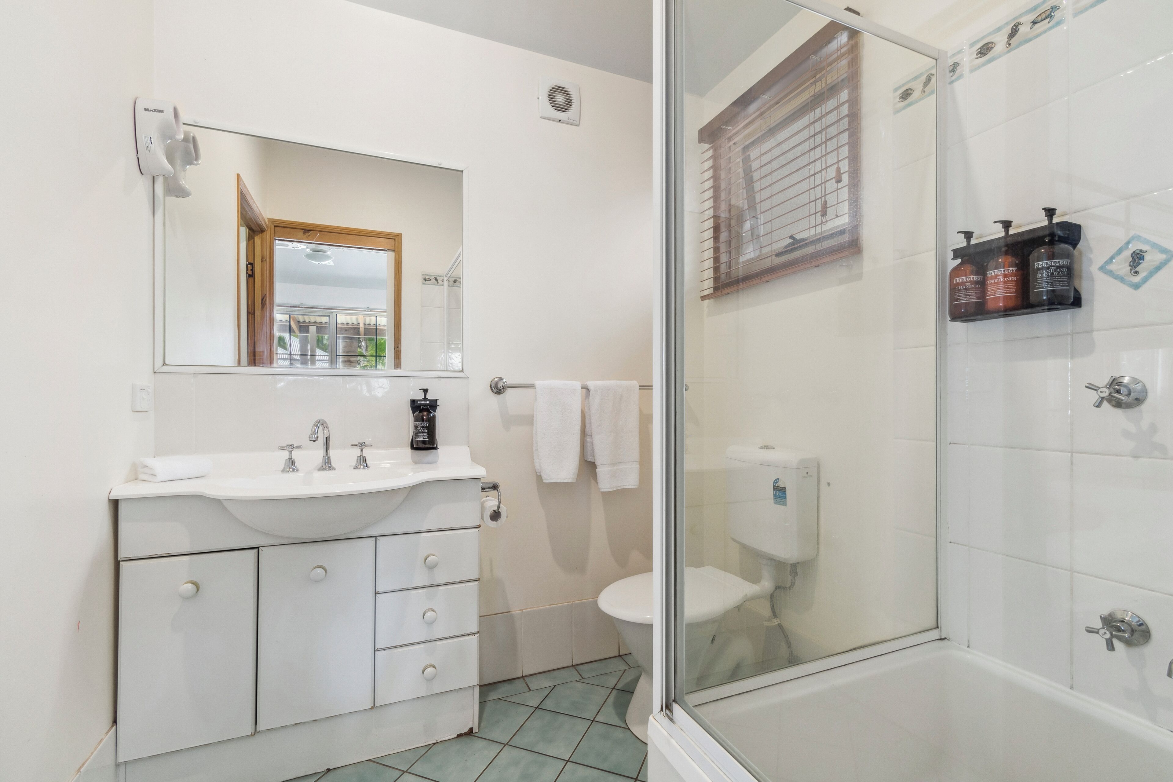 A bathroom with a white sink, mirror, and glass-enclosed shower.