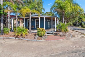 A two-story house with a porch, surrounded by palm trees and a small garden. - Batemans Bay Marina Resort (Batemans Bay)