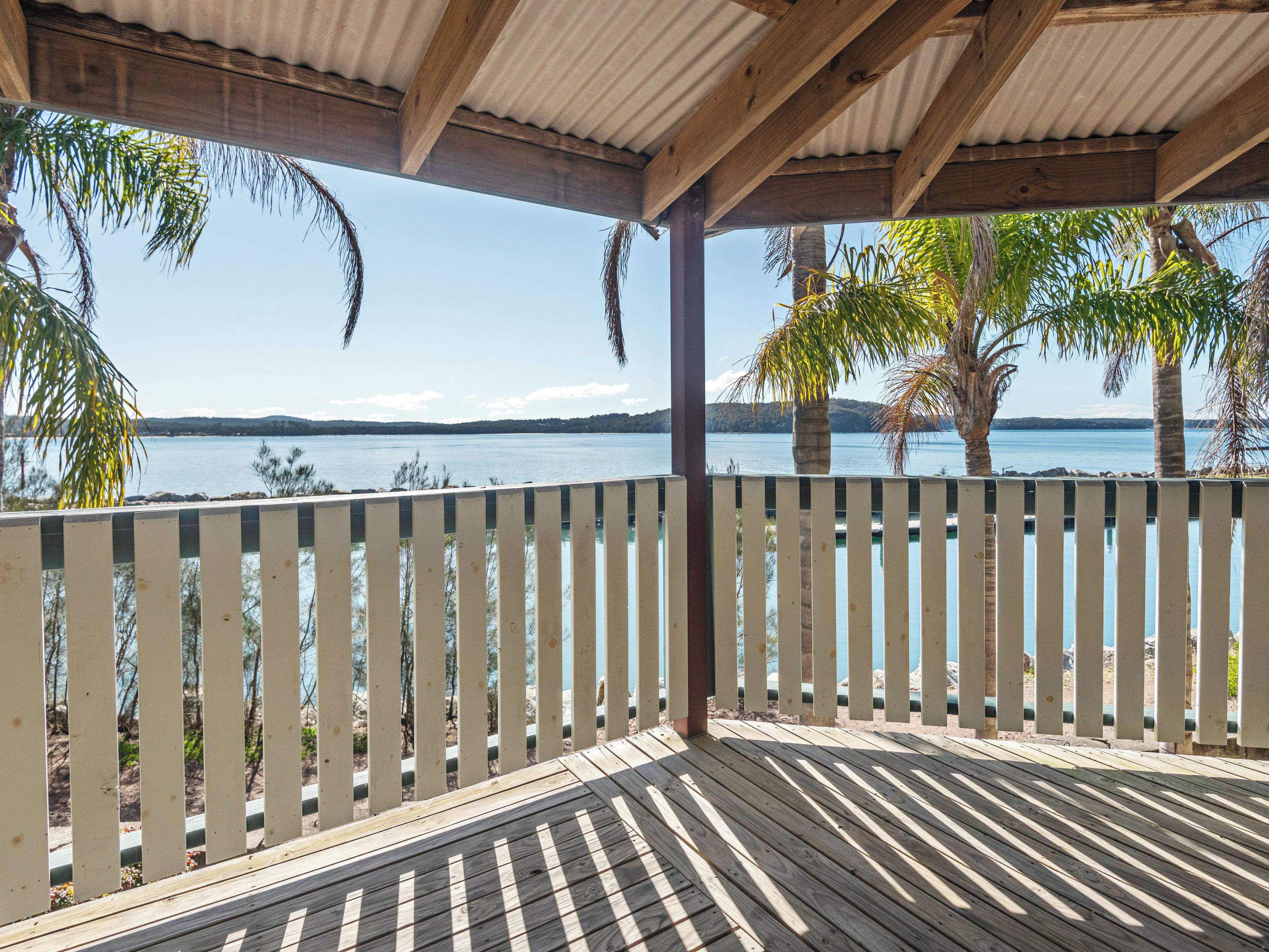 A wooden deck with a view of a calm lake and distant hills.