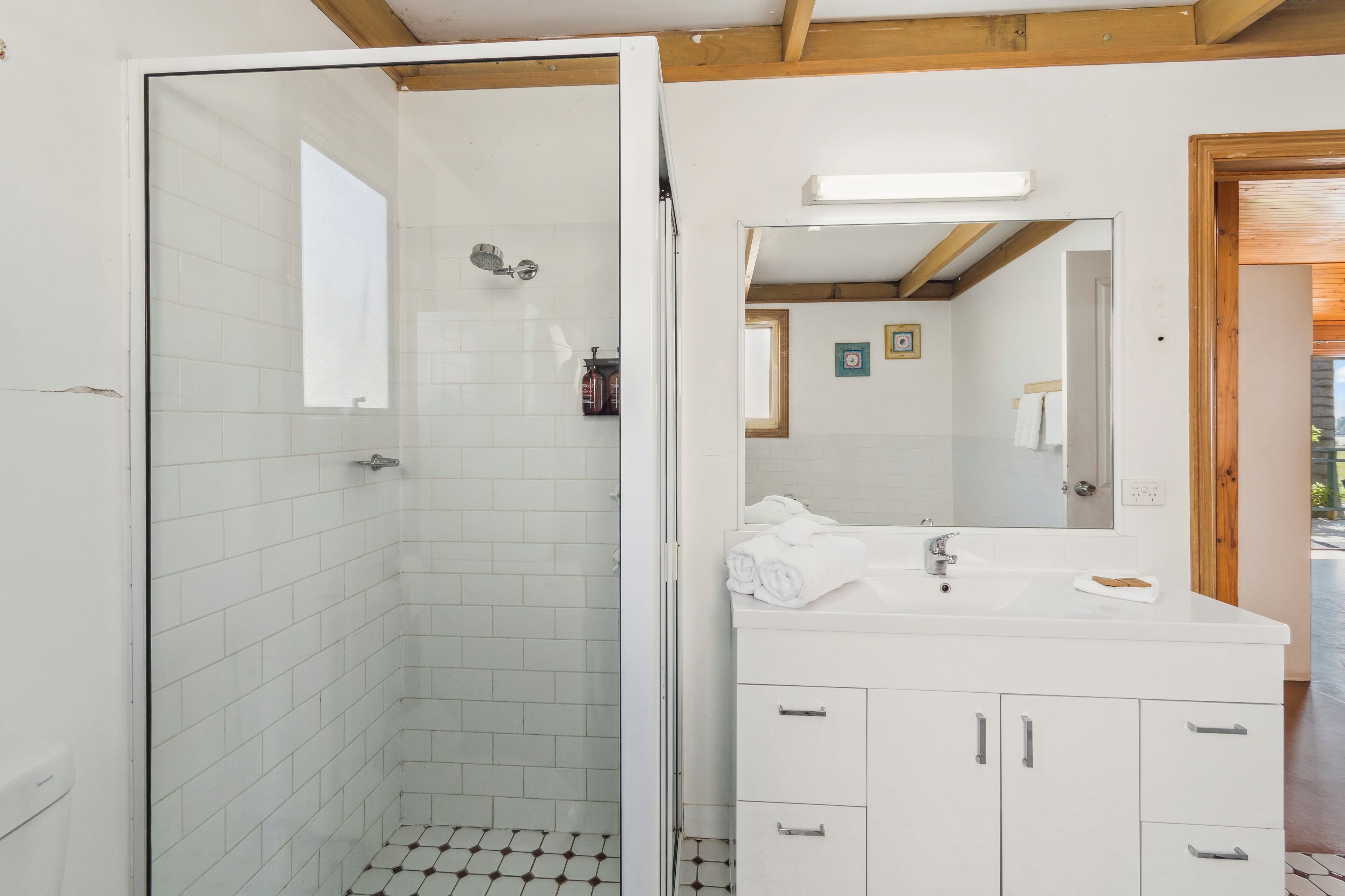 Ein Badezimmer mit Dusche, Waschbecken und Spiegel.