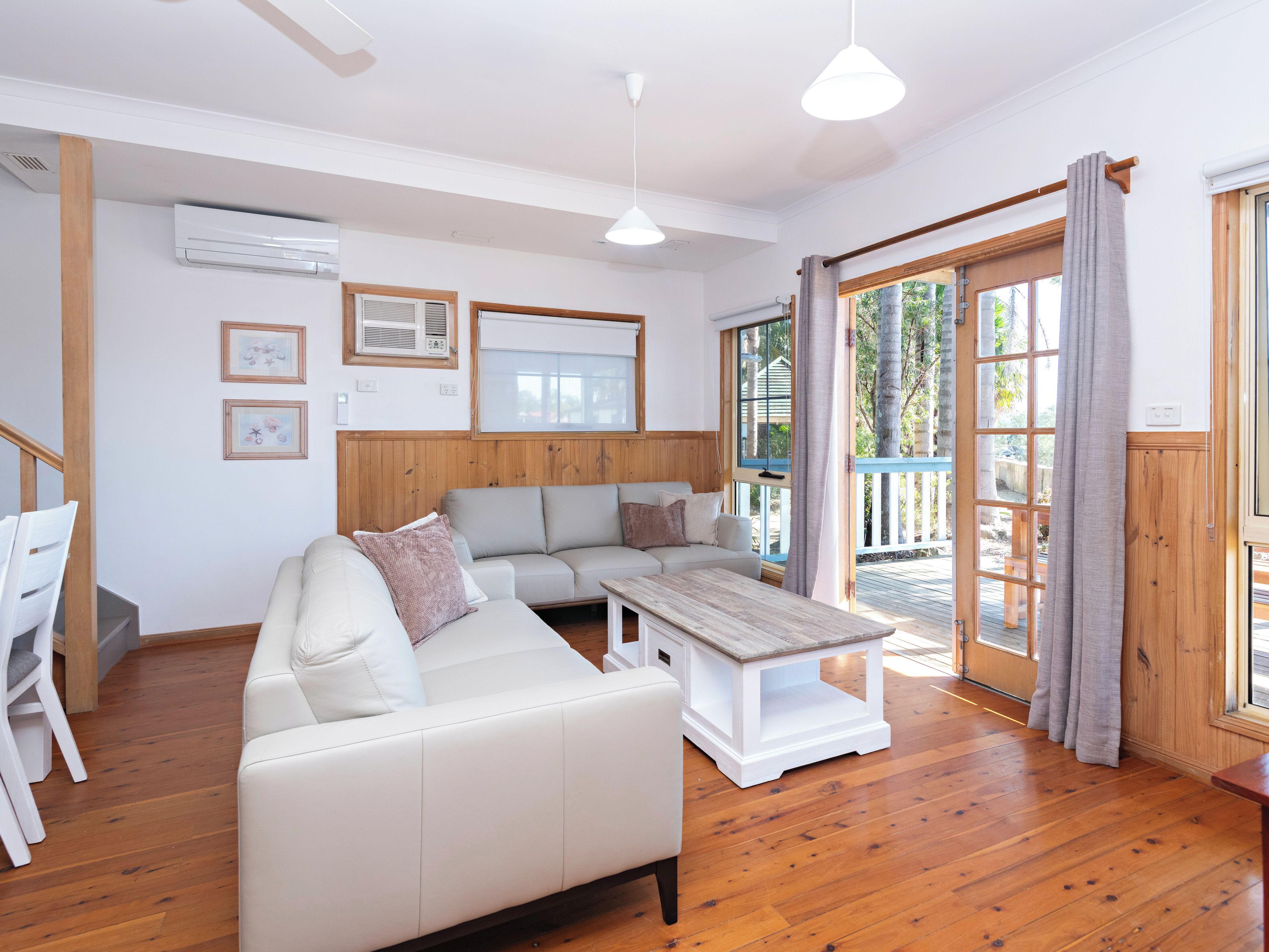 Una sala moderna con sofá, una mesa de centro y vistas al exterior a través de un ventanal corredero.