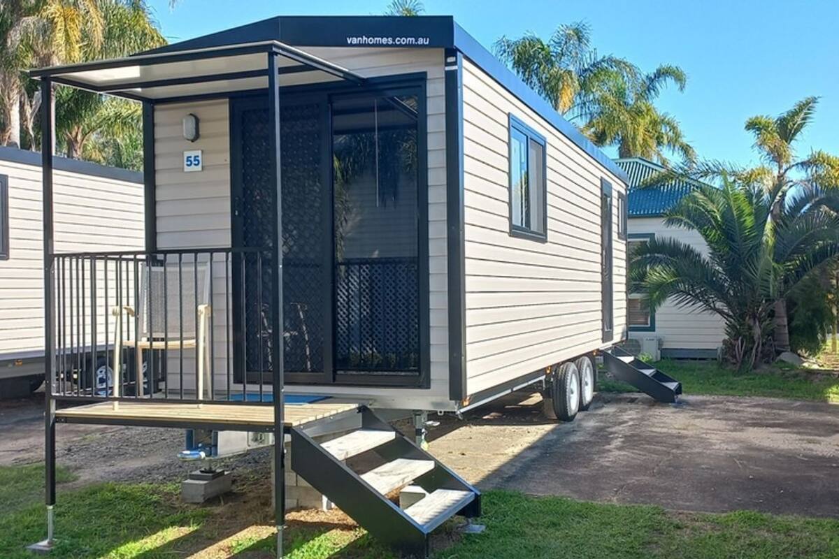 A mobile home with a covered porch and a small staircase leading to the entrance.