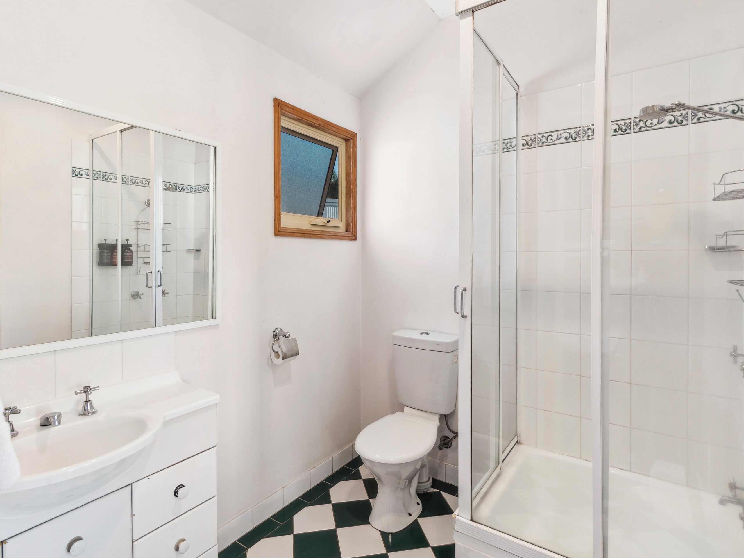 Un baño con lavamanos, inodoro y ducha blancos.