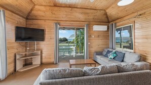 Un interior de madera con sofá, televisor y vistas al exterior.