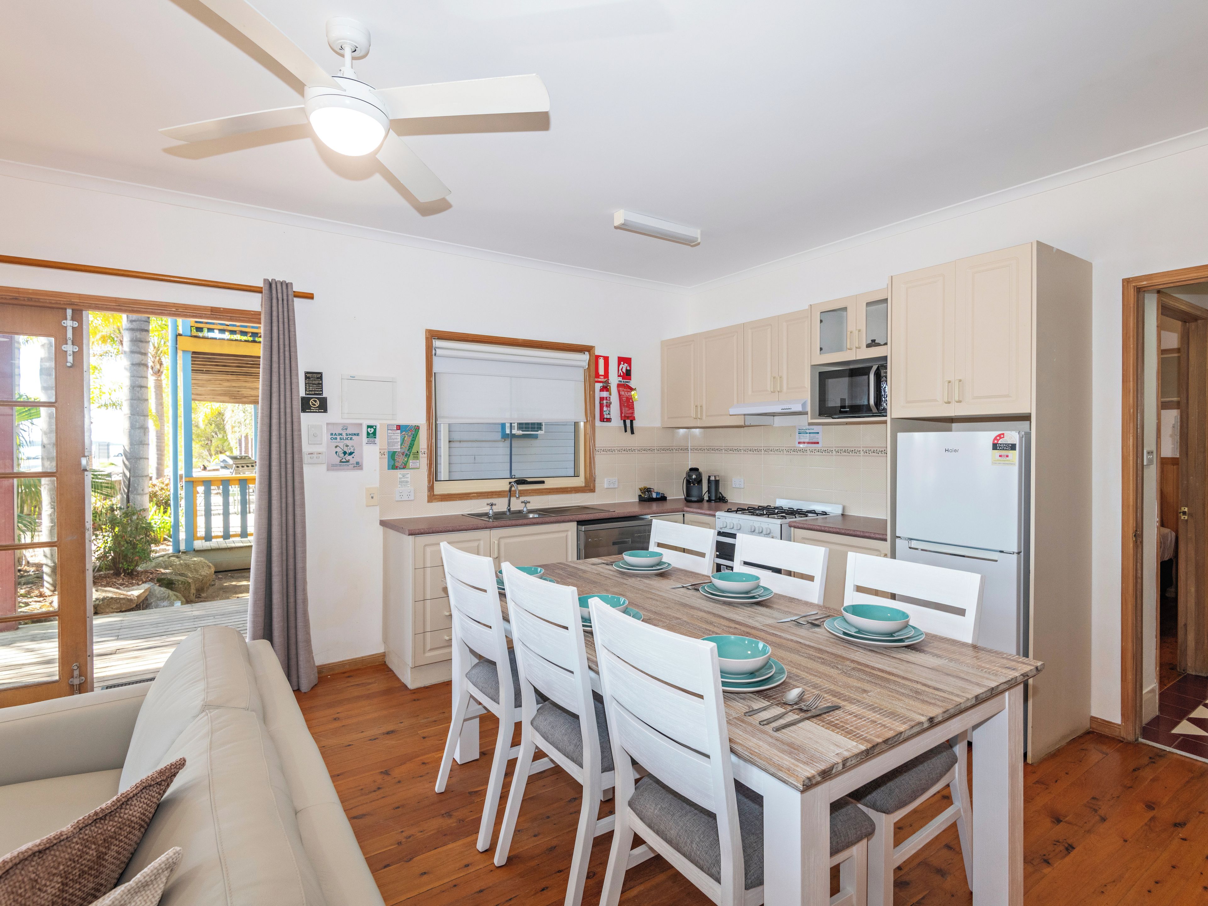 Una cocina moderna con zona de comedor, suelo de madera y ventilador de techo.